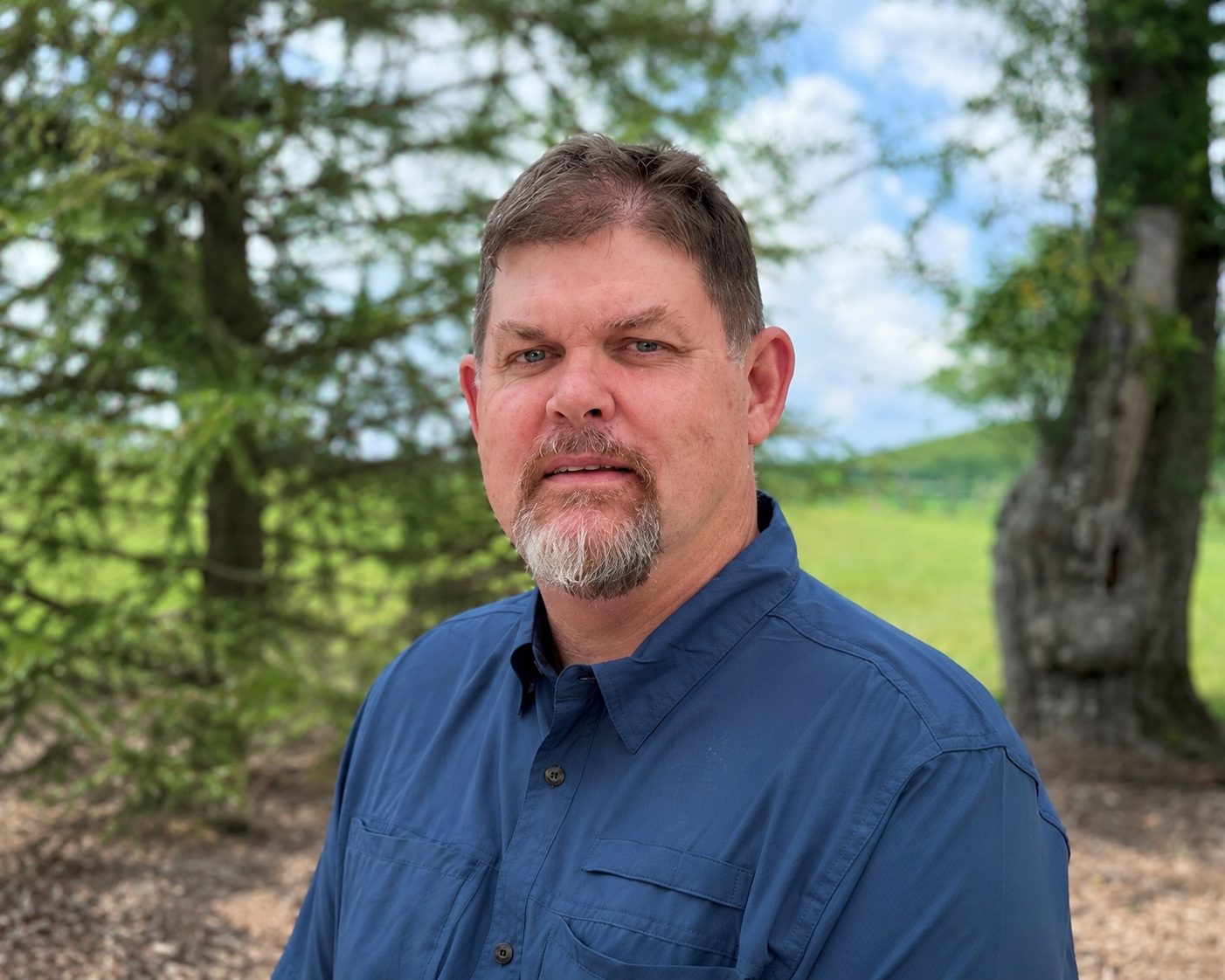 Man outdoors with trees in background.