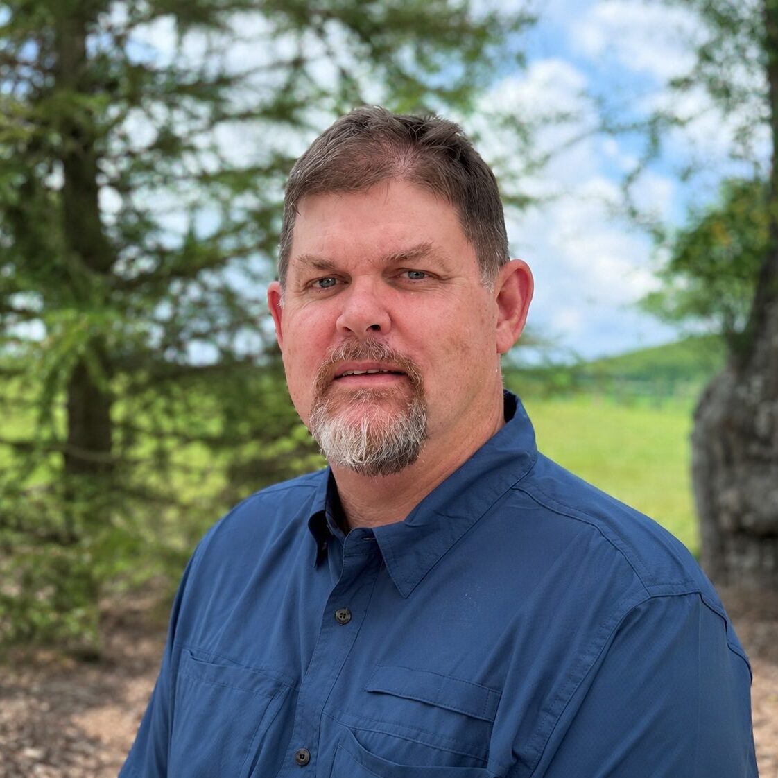 Man outdoors with trees in background.
